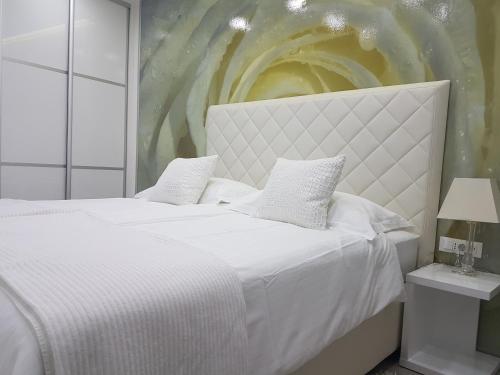 1 dormitorio con 1 cama blanca y una pintura en la pared en Palladium City Center Apartments, en Makarska