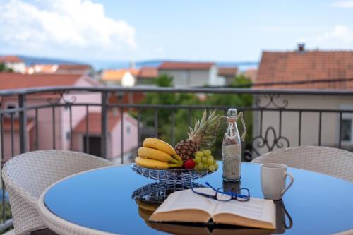a table with a bowl of fruit and a book on a balcony at Villa Apartments Kordić in Kaštela