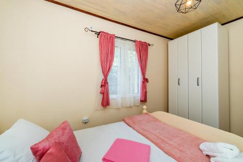 a bedroom with a bed with pink sheets and a window at Guest House Luna in Virpazar