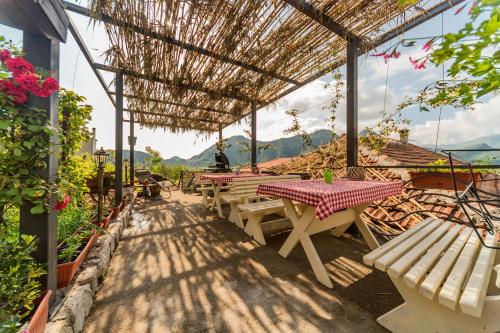 a group of tables and benches under a straw roof at Guest House Luna in Virpazar
