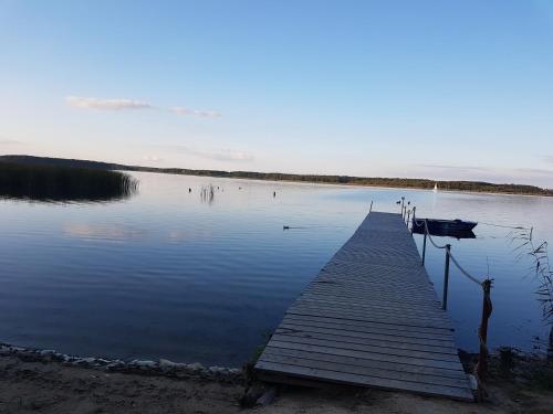 a dock on a lake with a boat in the water at Yacht Club Apartamenty in Radzyń