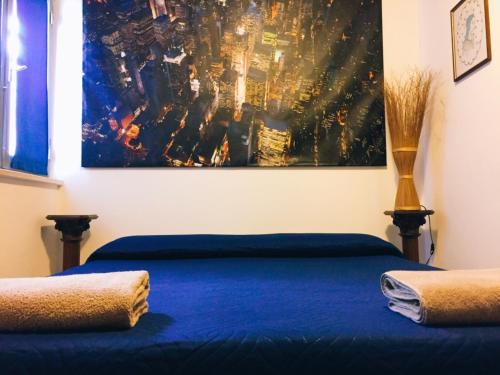 a bedroom with a blue bed with a painting on the wall at B&B dell'Amicizia in Fano