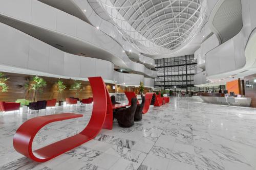 a lobby with red chairs in a building at Royal Tulip Brasília Alvorada in Brasilia