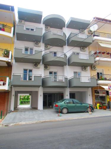 a green car parked in front of a building at Artistic Rent Rooms & Apartments in Nea Kalikratia