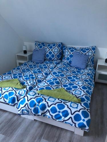 een bed met blauwe en witte lakens en kussens bij Marci Apartman in Balatonboglár