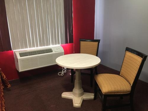 a room with a table and two chairs and a fan at Journeys End Motel in Absecon