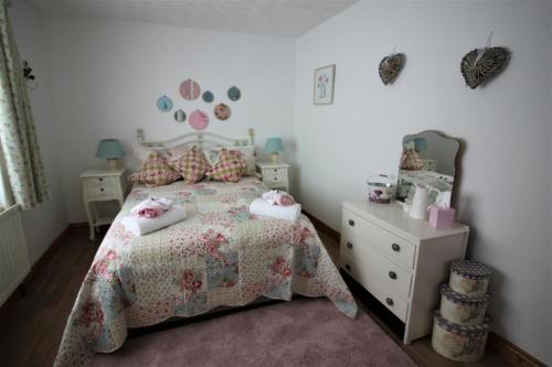 a small bedroom with a bed and a dresser at Maggies Cottage in Bushmills