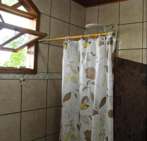 cortina de ducha en un baño con ventana en Jardim das orquídeas en Mucugê