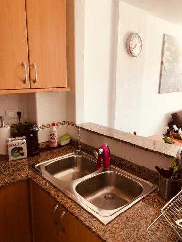 Apartamento Solmar في بينييسكولا: طاولة مطبخ مزودة بحوض وساعة معلقة على الحائط