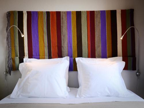 a bed with two white pillows and a colorful headboard at Train Spot Guesthouse in Marvão