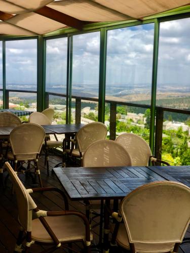 a group of tables and chairs in a room with windows at pisgat shoresh in Shoresh