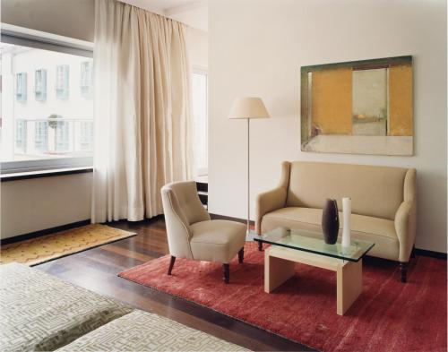 a living room with a couch and a table and a chair at Hotel Greif, a Member of Design Hotels in Bolzano
