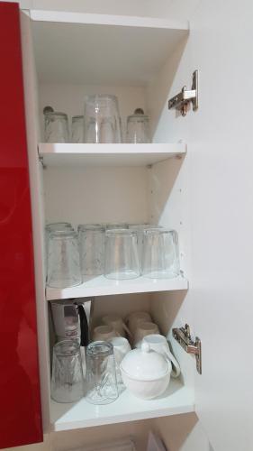 a white cabinet filled with glass jars and bowls at Kariat Cabo - Appartement Charmant, Climatisé avec Vue Piscine in Cabo Negro