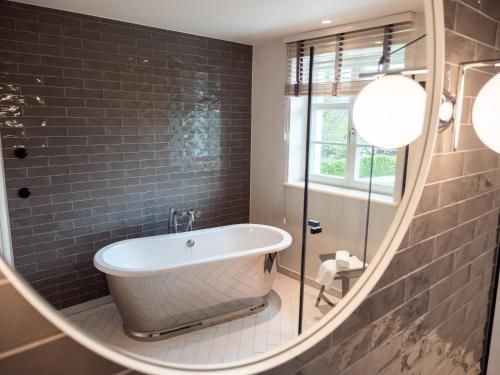 a bathroom with a tub in a round mirror at Alpenloge Design Hotel in Scheidegg