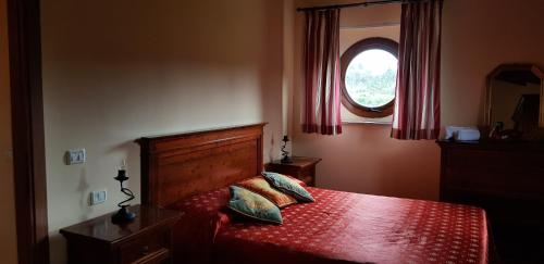 a bedroom with a bed with a red comforter and a window at Poggio Al Palio in San Lorenzo a Merse