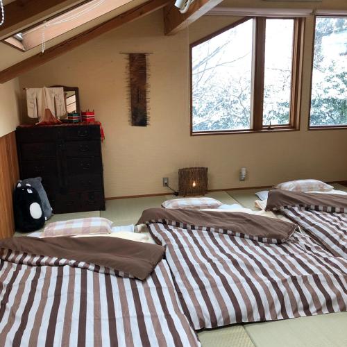 a room with three beds and a dresser and windows at ガーデンハウス Mako Land in Toyama