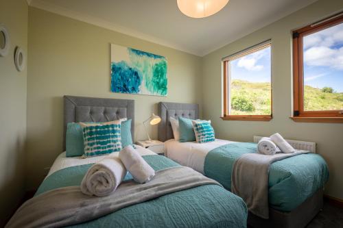 two beds in a room with two windows at Taste of the Sea in Staffin