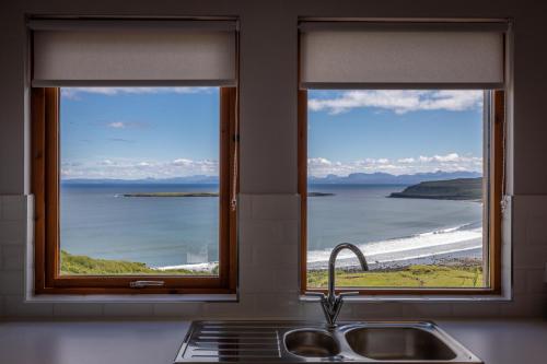 a kitchen sink with two windows with a view of the ocean at Taste of the Sea in Staffin