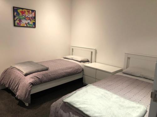 メルボルンにあるEPIC Private Apartmentのベッドが2つあり、壁に絵が飾られている寝室