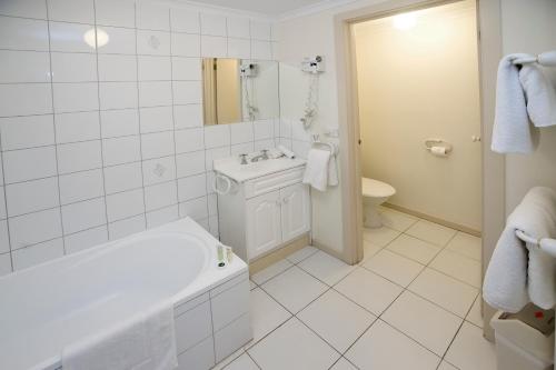 a white bathroom with a tub and a sink at Hawthorn Gardens Serviced Apartments in Melbourne