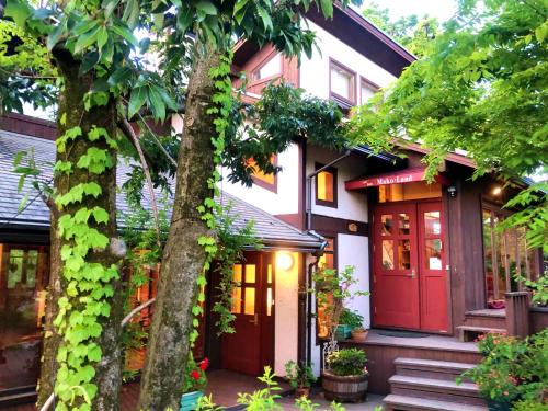 ein Haus mit einer roten Tür und einem Baum in der Unterkunft ガーデンハウス Mako Land in Toyama
