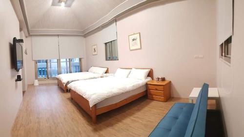 1 dormitorio con 2 camas y sofá azul en JiuZhiAn Apartment, en Wujie