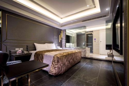 a hotel room with a bed and a television at OUGE Motel - Fengshan in Kaohsiung