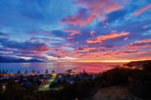 a view of a city with a sunset over the water at A Room With a View in Kaikoura