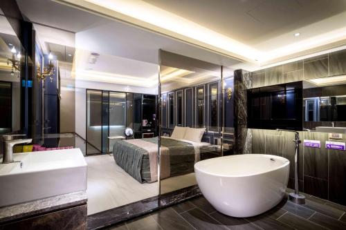 a bathroom with a tub and a bed and a sink at OUGE Motel - Fengshan in Kaohsiung