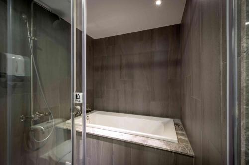 a bath tub in a bathroom with a shower at OUGE Motel - Fengshan in Kaohsiung