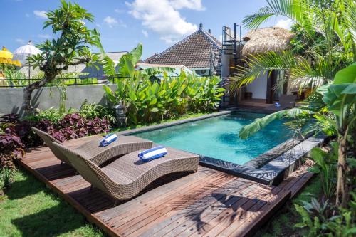 a backyard with a swimming pool and a wooden deck at Kak Poleng Guesthouse in Canggu