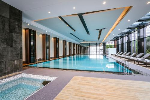 a swimming pool in a building with chairs at Pullman Shanghai Jing'an-Jing'an district, downtown railway station, traffic hub, easy to travel Shanghai in Shanghai