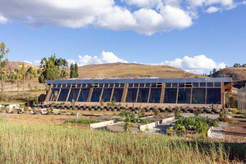 a building with a bunch of plants in a field at Casa 100% ecológica con vista a los glaciares andinos in Maras