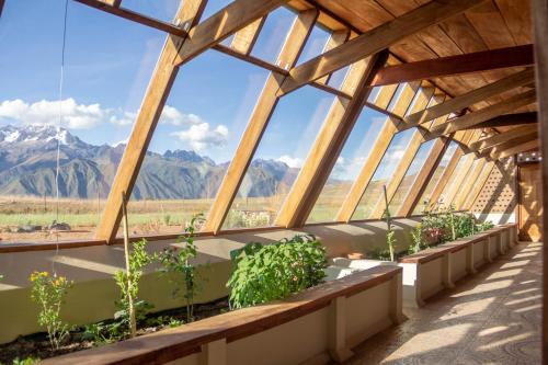 a greenhouse with plants and mountains in the background at Casa 100% ecológica con vista a los glaciares andinos in Maras