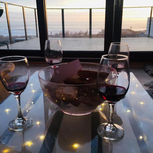three glasses of wine on a table with a view at PUPUYA LODGE cabaña A, Matanzas in Matanzas