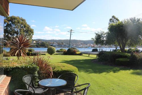 a patio with a table and chairs and a view of the water at Pelican Waters in Merimbula