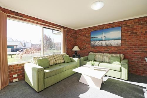 a living room with two couches and a brick wall at Pelican Waters in Merimbula