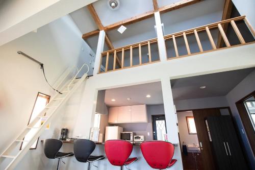 a living room with red chairs and a staircase at Tabi no Yado in Nakijin