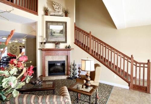 a living room with a fireplace and a staircase at GrandStay Residential Suites Hotel Faribault in Faribault