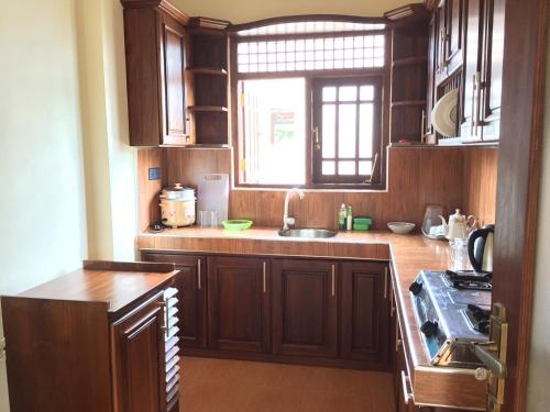 a kitchen with wooden cabinets and a sink and a window at Sweet Home Tourist Rest, Cooking Classes & Tours in Anuradhapura