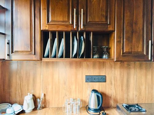 a kitchen counter with wooden cabinets with white dishes at Sweet Home Tourist Rest, Cooking Classes & Tours in Anuradhapura