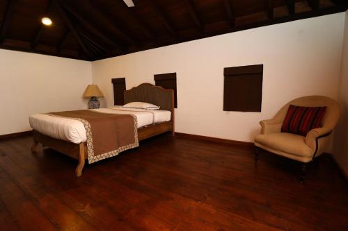 a bedroom with a bed and a chair at The Postcard Galle in Galle
