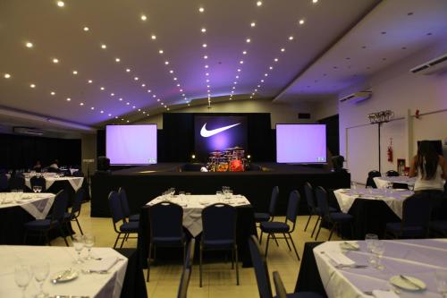 a room with tables and chairs and a stage with screens at Convair Hotel in Ciudad del Este