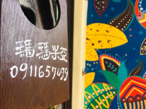 a wooden sign in front of a colorful wall at Mamamia Homestay in Hengchun