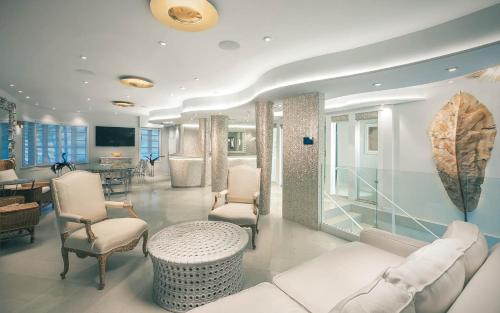 Il comprend un salon doté d'un mobilier blanc, d'une table et de chaises. dans l'établissement Cardozo Hotel, à Miami Beach