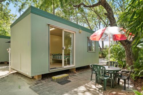 a green tiny house with a table and an umbrella at Riverview Tourist Village in Katherine
