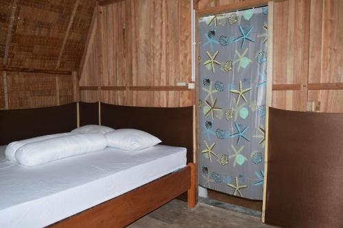 Habitación pequeña con cama y cortina en Tanjung Kalemo Resort en Batudaka