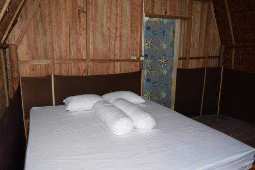 a bed with white pillows on top of it at Tanjung Kalemo Resort in Batudaka