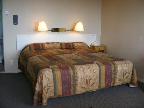 a bedroom with a bed with two lights on the wall at Hotel Motel Bon Accueil in Rivière-la-Madeleine