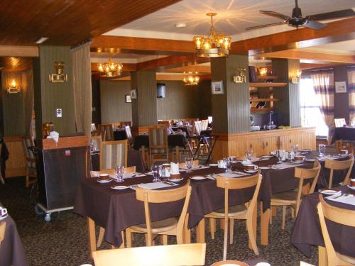 a dining room with tables and chairs in a restaurant at Hotel Motel Bon Accueil in Rivière-la-Madeleine